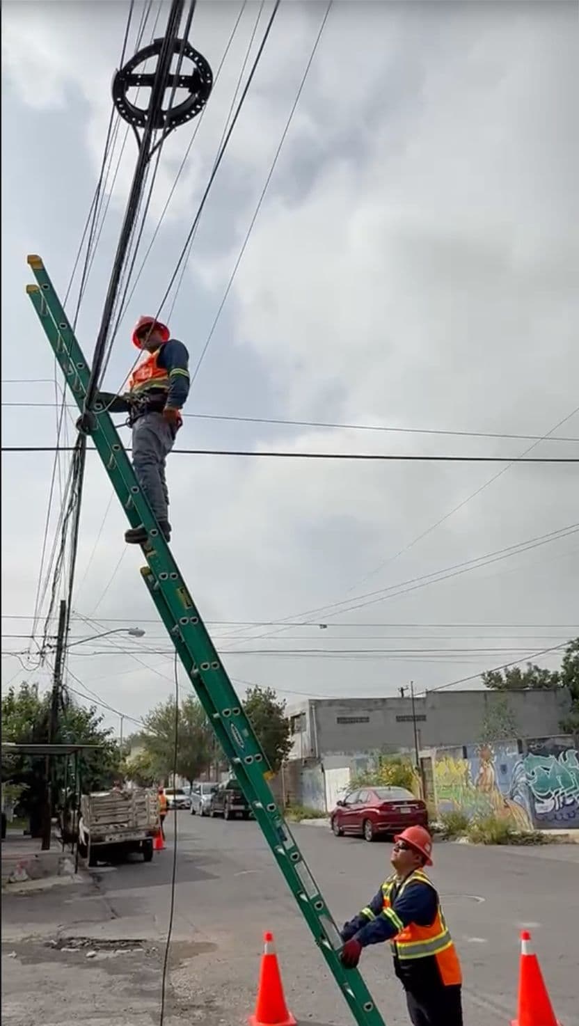 Técnicos realizando tendido aéreo de fibra óptica con una escalera